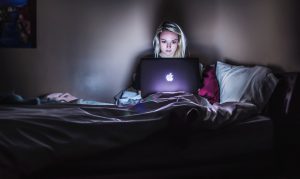 Person in bed working on laptop to show balanced work-life is essential