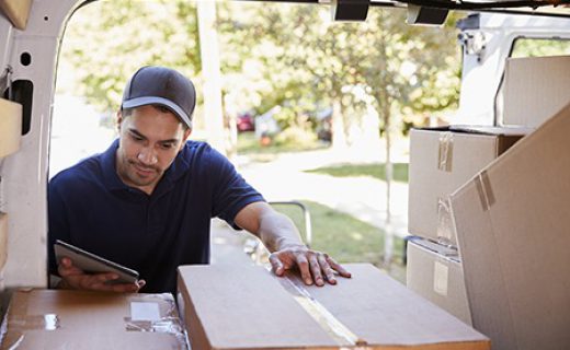 Courier With Digital Tablet Checking Packages In Van Courier With Digital Tablet Checking Packages In Van