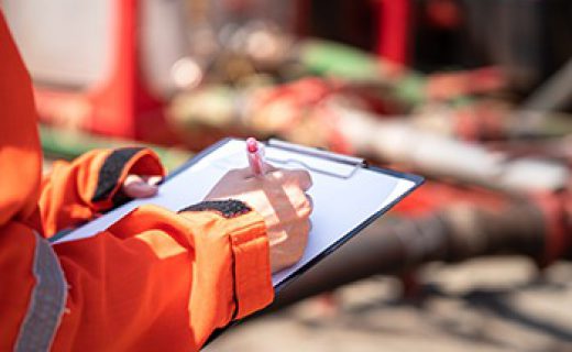 Safety officer or Supervisor is writing note on the checklist paper during perform audit and inspection in oil field operation. Close-up action and selective focus photo.
