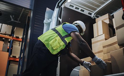 Handsome,Black,Male,Retail,Warehouse,Worker,Loads,Cardboard,Boxes,In Handsome Black Male Retail Warehouse Worker Loads Cardboard Boxes in Delivery Truck. Logistics Retail Center, Delivering e-Commerce Online Orders, Food and Medicine Supply. Low Angle Evening Shot