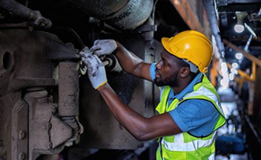 Engineer railway wearing safety gear checking train transmittal system for safety travel passenger